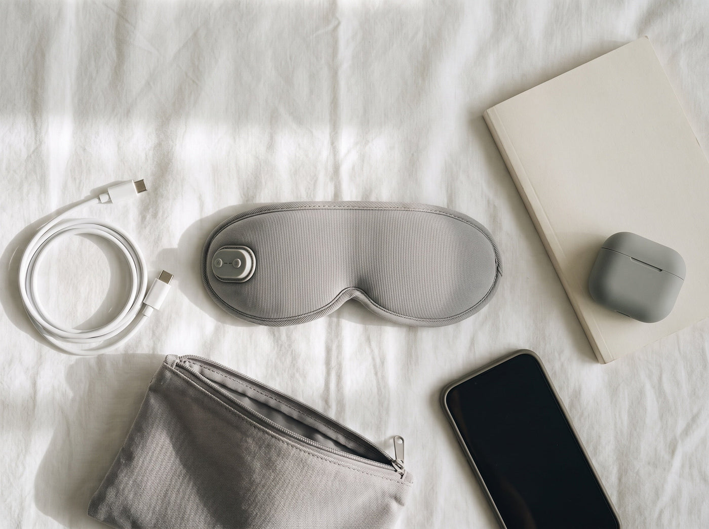 Eye mask, charging cable and travel essentials arranged for packing