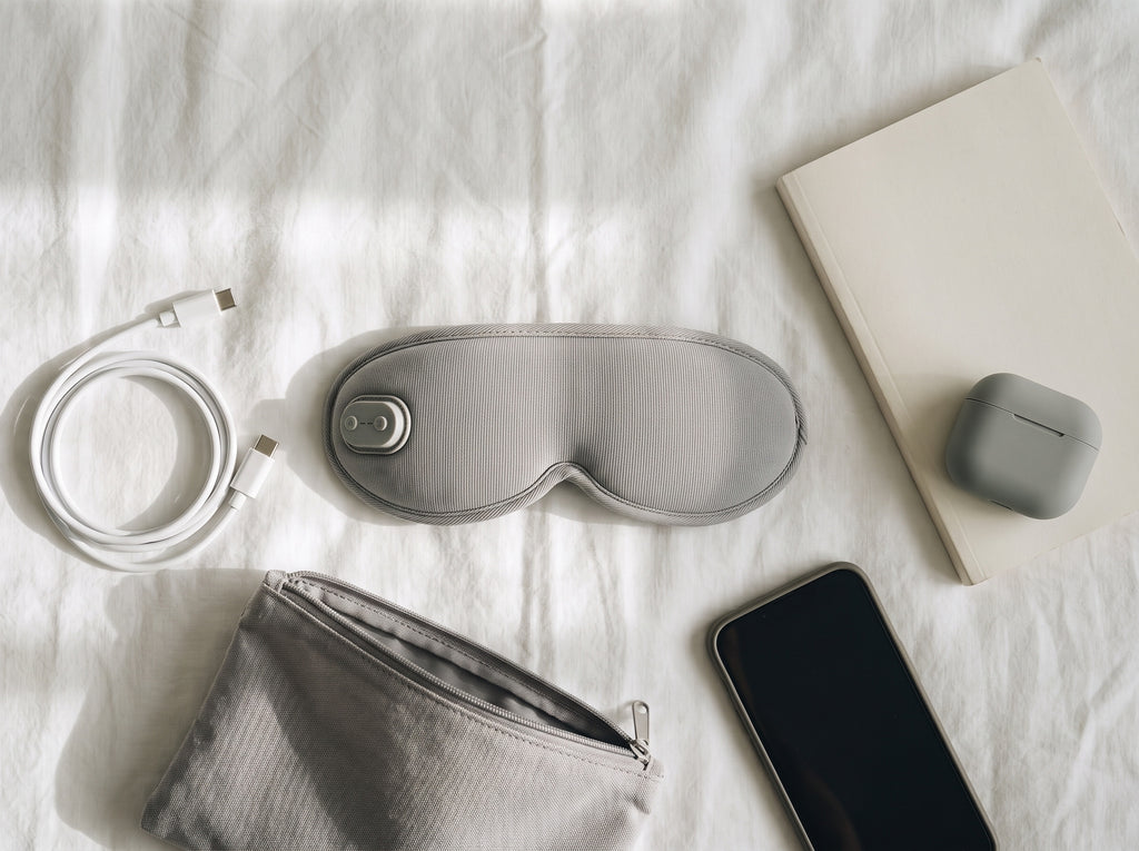 Eye mask, charging cable and travel essentials arranged for packing