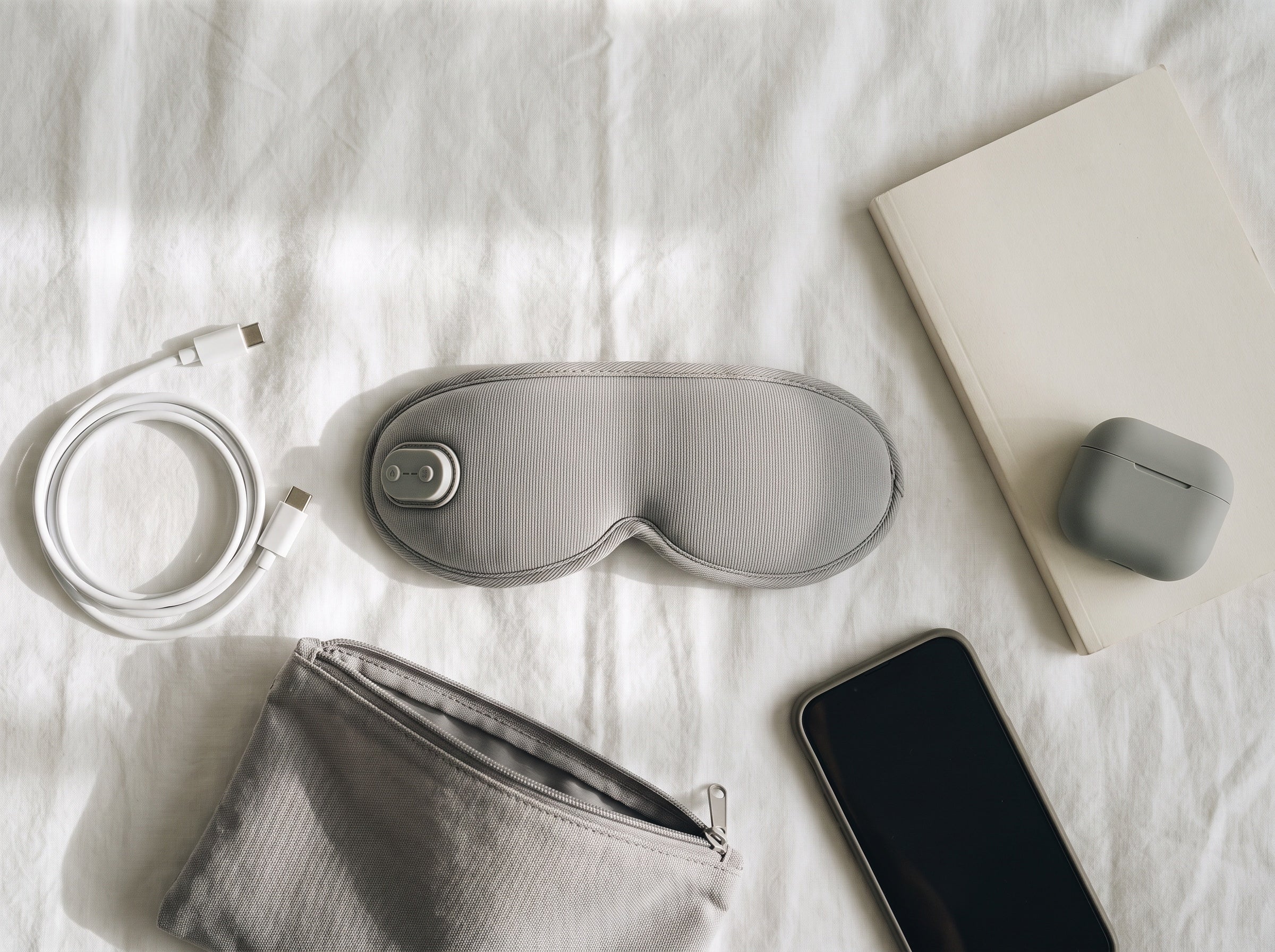 Eye mask, charging cable and travel essentials arranged for packing