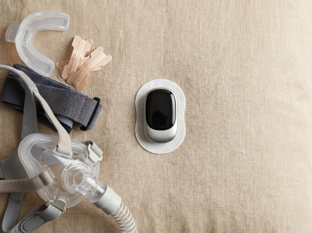 A flatlay comparing a bulky mouthguard, nasal strips and a CPAP mask with the compact Quietvana device